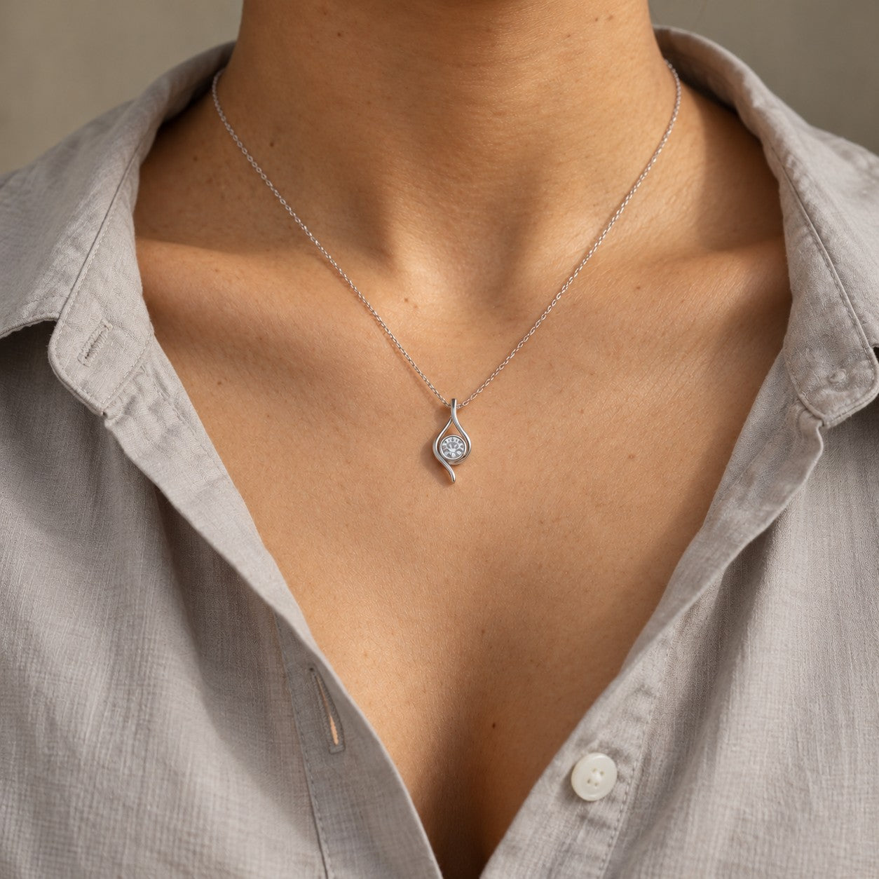 Eterna Flame silver flame teardrop pendant worn on the neck with a grey cotton shirt, Silvk 925 silver jewellery