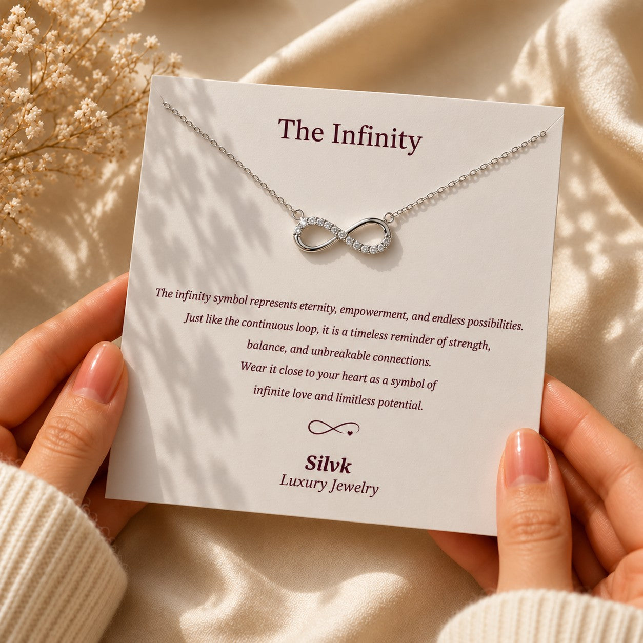 The Infinity pendant on its message card held in two hands, Silvk 925 silver jewellery