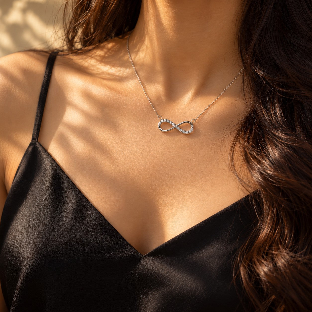 The Infinity silver pendant worn on the neck with a black silk camisole, Silvk 925 silver jewellery