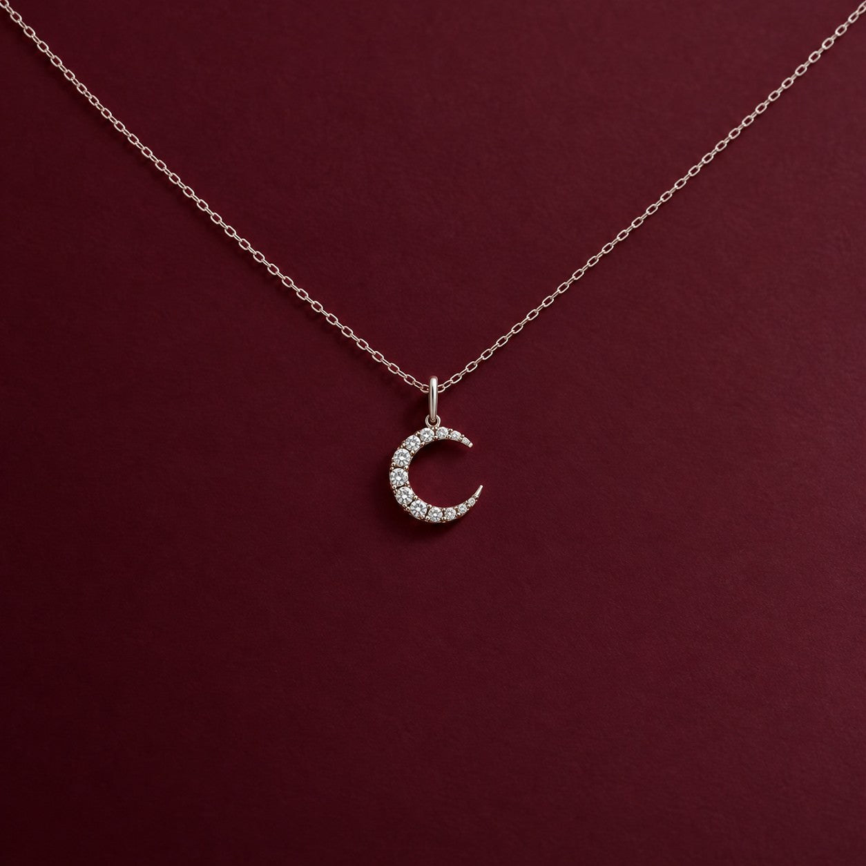 The Moon silver crescent pendant on a deep burgundy background, Silvk 925 silver jewellery