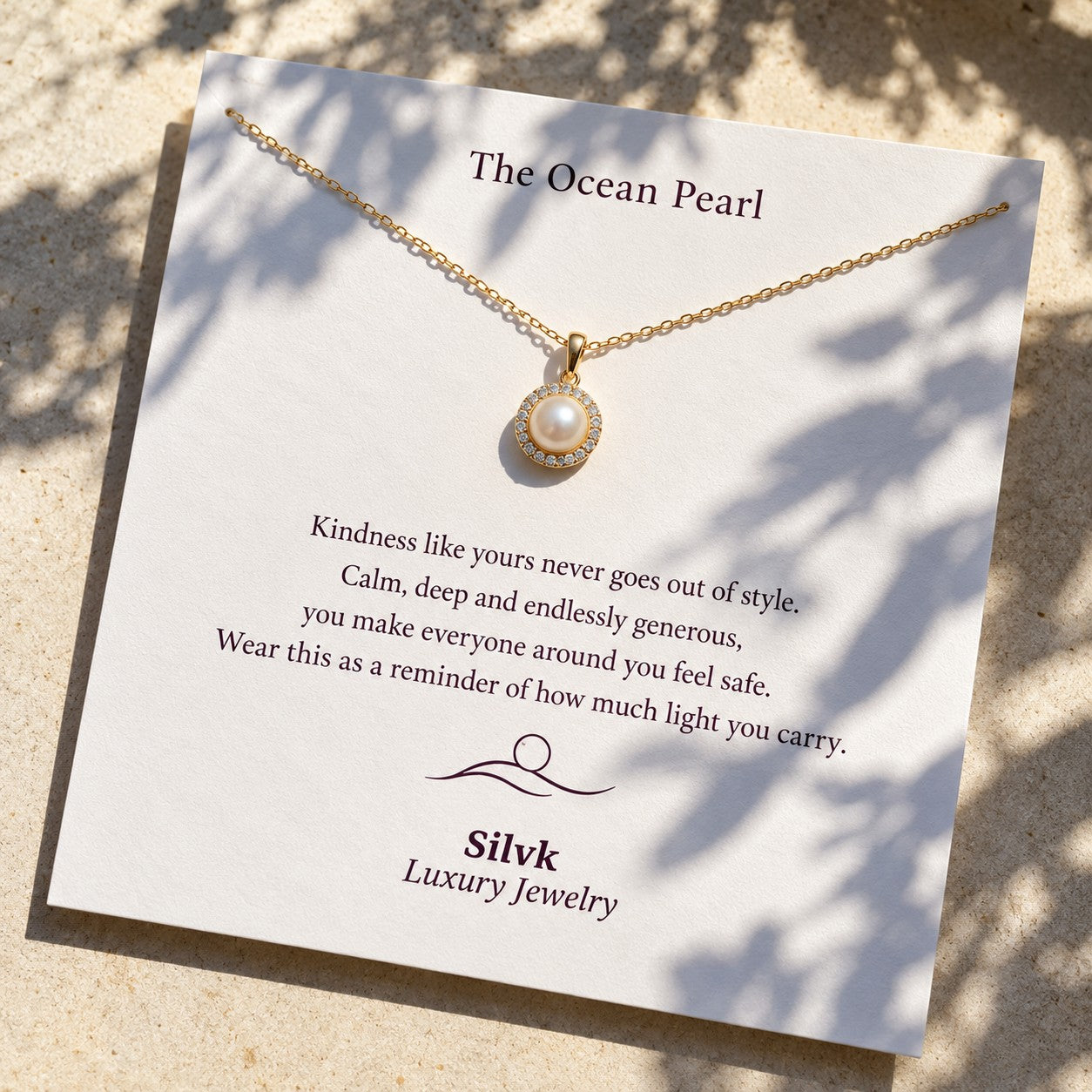 The Ocean Pearl gold pendant on its message card in sunlight, Silvk 925 silver jewellery